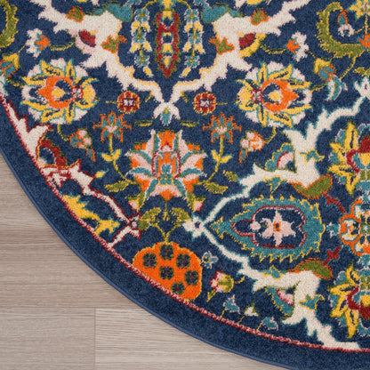 Round navy blue oriental rug with vivid floral motifs in orange, yellow, green and white; bound edge on wood floor.