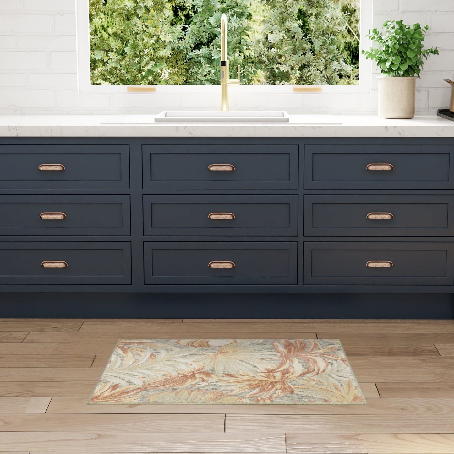 Navy blue shaker cabinets with copper handles, white countertop, gold faucet, tropical floral rug on wood floor.