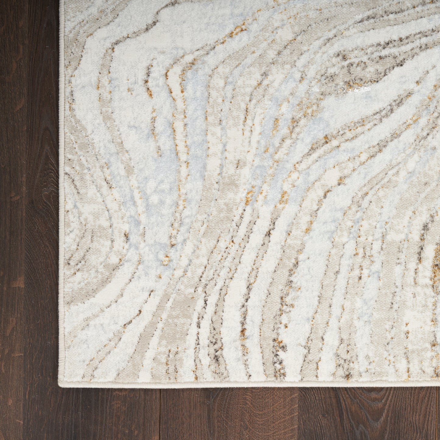 Abstract wavy-line area rug in neutral beige, gray and ivory tones on dark wood floor.