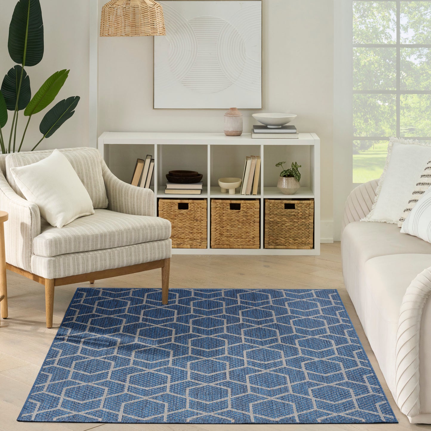Coastal living room featuring blue geometric rug, beige striped armchair, white cubed storage with wicker baskets.