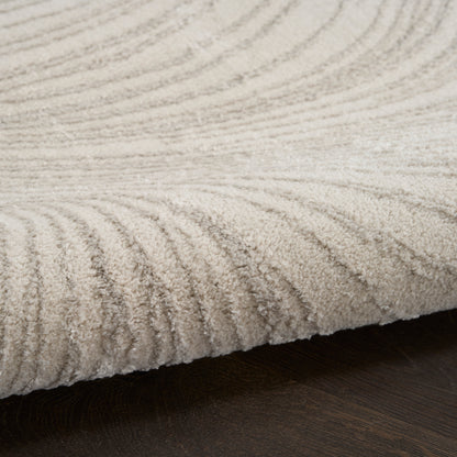 Cream rug with plush, ribbed texture and subtle linear pattern on dark wooden floor.