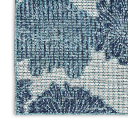 Close-up of blue floral jacquard rug with turquoise border edge.
