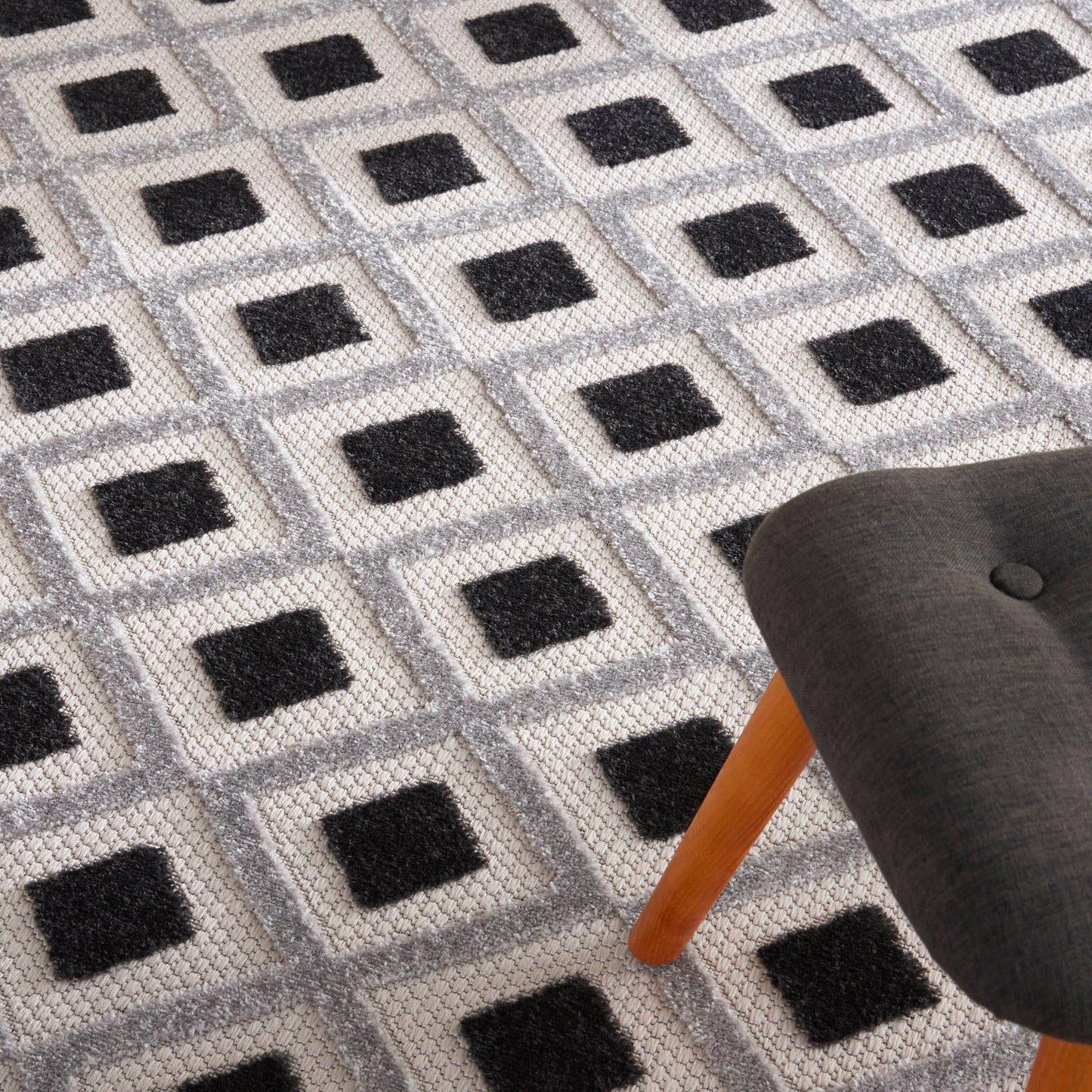 Textured gray rug with black square motifs in a grid.