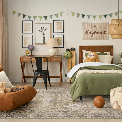 Vintage 8' x 10' rug in a cozy kids' bedroom scene with a wooden bed, olive-green comforter, plush monkey, desk with globe, framed art, and bunting garland.