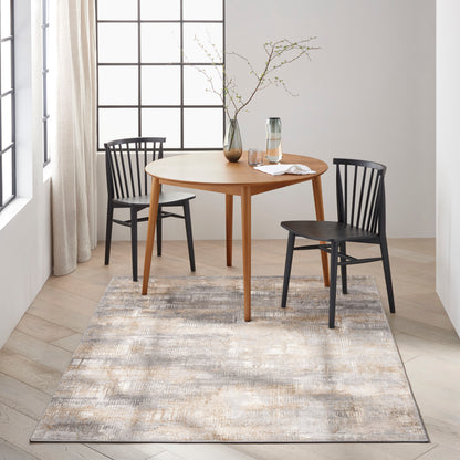 Beige-gray rug on floor with a glass carafe and a vase with branches; partial view of a round dining table and two black spindle chairs.
