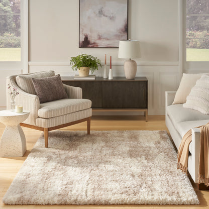 Neutral-toned living room with cream striped armchair, beige rug, light-gray sofa, dark wood sideboard, plant and candles.