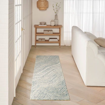 Light blue-gray woven runner rug with chevron pattern along pale wood floor in bright Scandinavian living room.