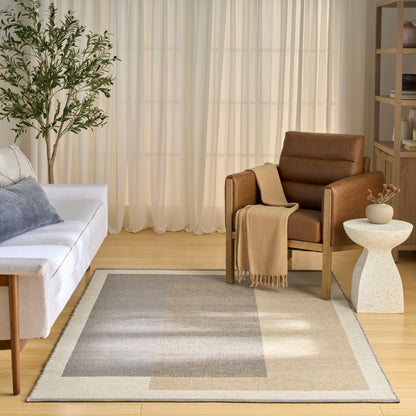 Cozy living room: white sofa, gray cushions, brown leather armchair with beige throw, beige-gray rug, plant, sheer curtains.