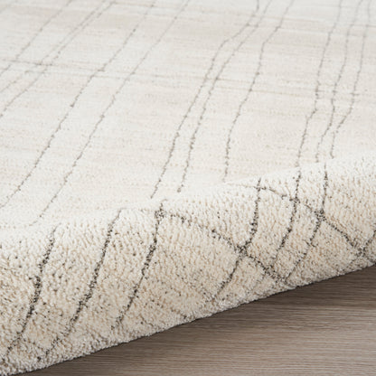 Cream shag rug with subtle gray linear grid pattern, plush pile, folded edge on wood floor.
