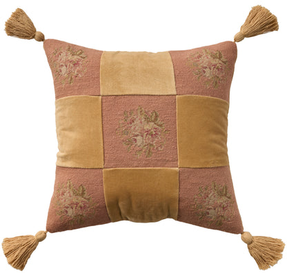 Decorative patchwork throw pillow with tassels at four corners; mustard yellow and dusty rose squares, floral embroidery.