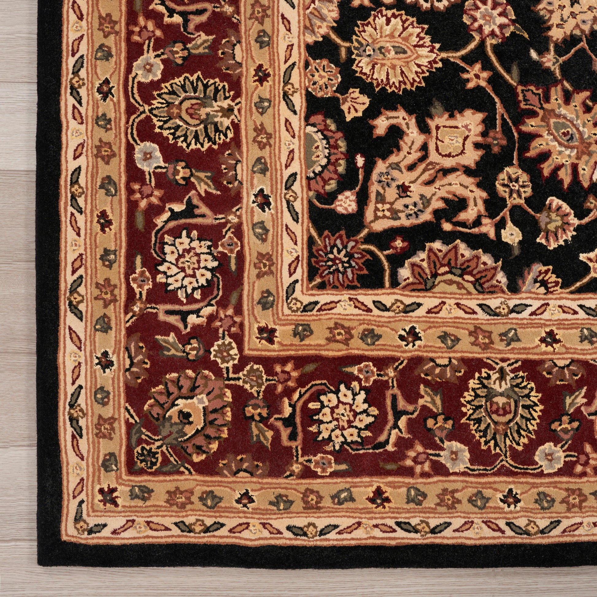 Close-up of a traditional Persian-style rug with a burgundy field, ornate floral motifs, and cream borders.
