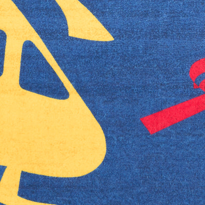 Close-up of royal blue rug featuring large yellow abstract shapes and a red ribbon element.
