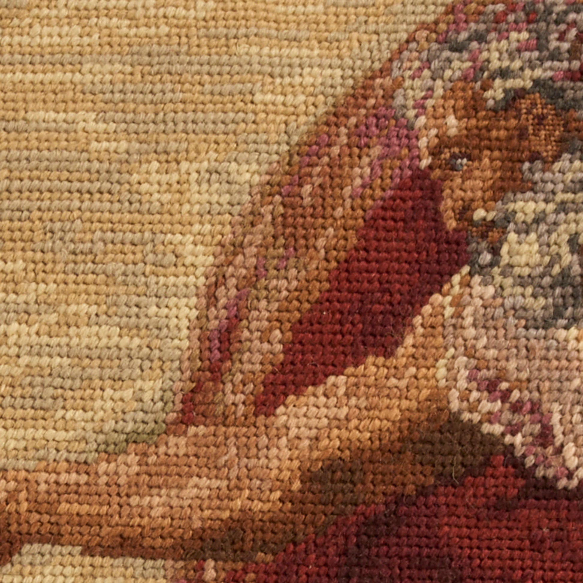 Close-up of a woven kilim-style rug with burgundy and brown geometric motifs on a beige background.