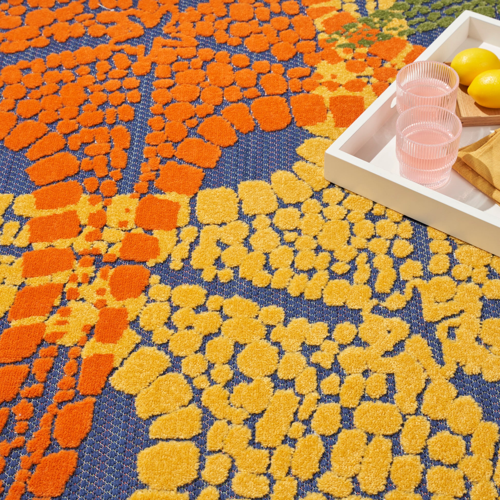 Vibrant outdoor rug with orange and yellow mosaic shapes on a blue background.