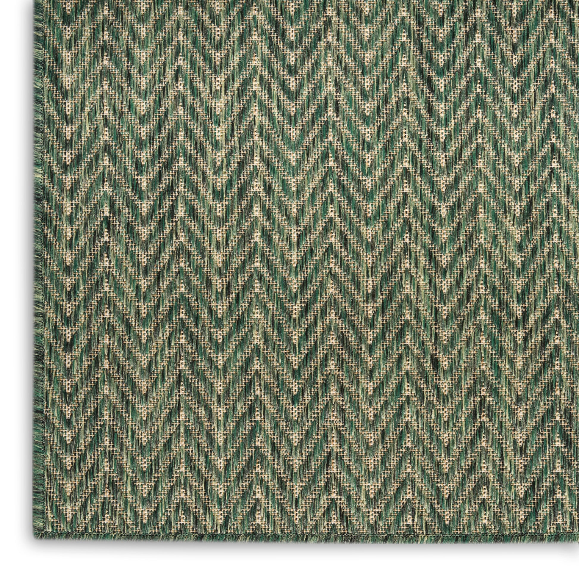 Close-up of green chevron woven rug with beige accents, zigzag pattern and textured fringe edge.