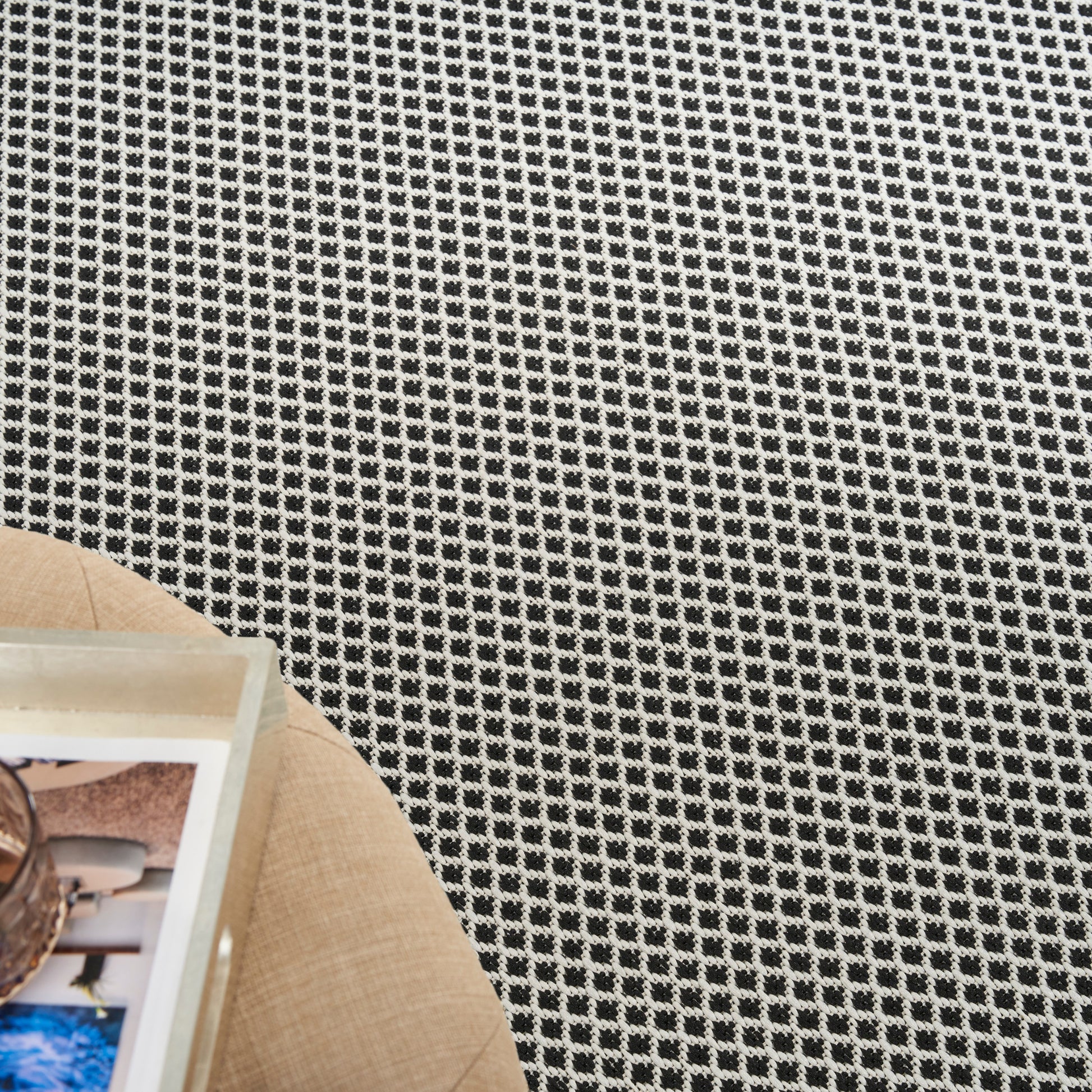 Black-and-white checkered woven rug texture on the floor.