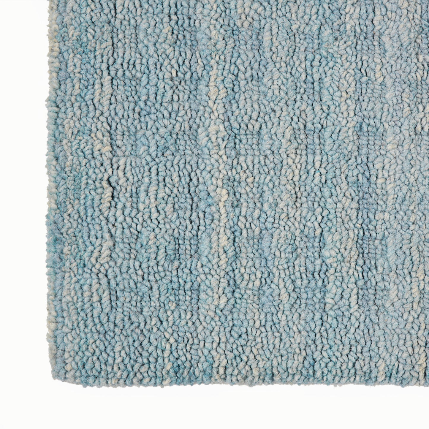 Close-up of a blue and cream shag rug with dense loop pile and variegated light blue fibers.