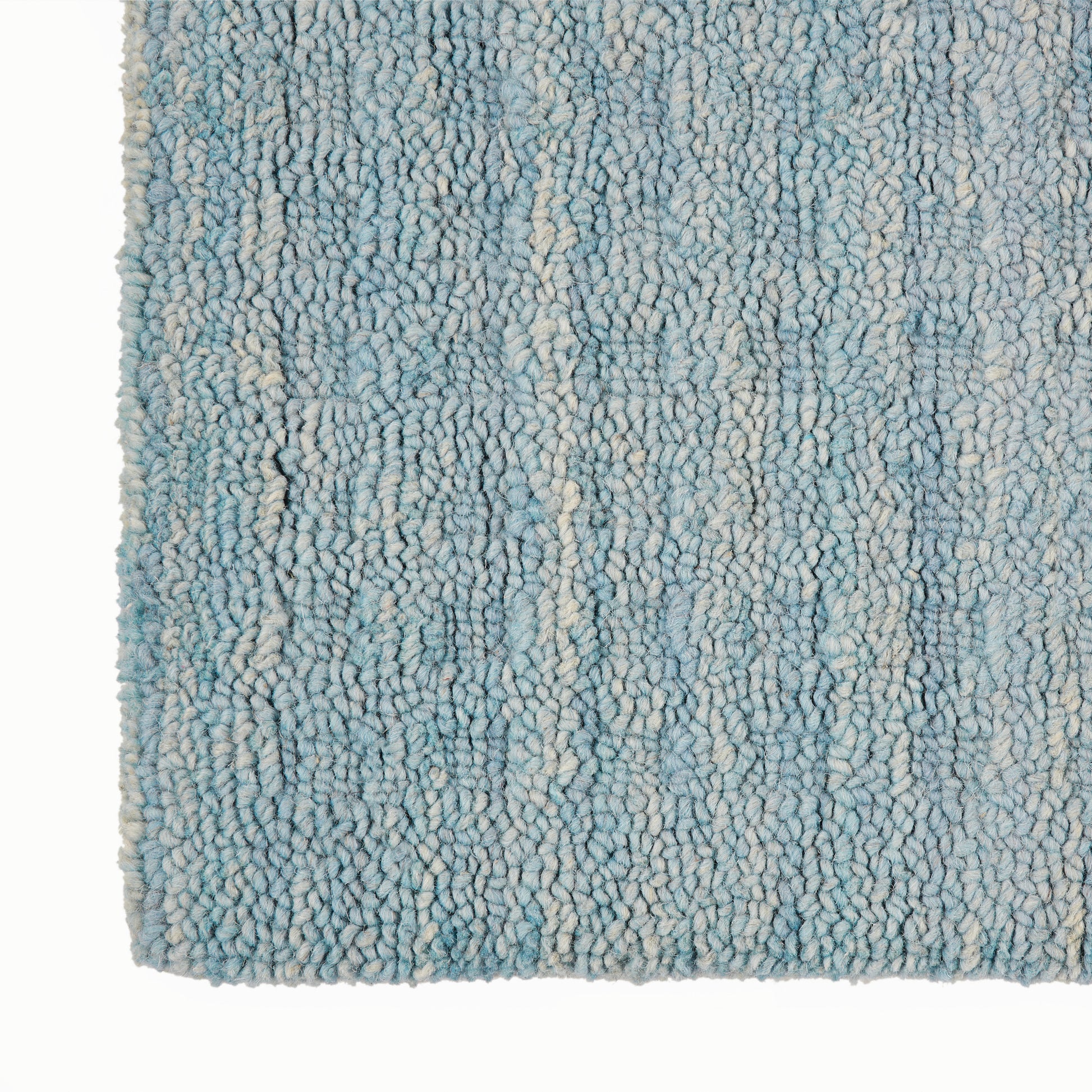 Close-up of a blue and cream shag rug with dense loop pile and variegated light blue fibers.