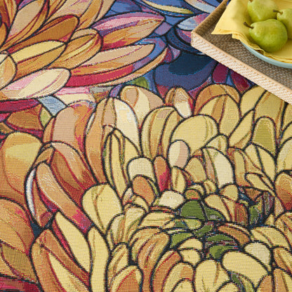 Colorful abstract floral tapestry pattern rug with yellow, orange, pink petals; tray with green pears on yellow napkin.