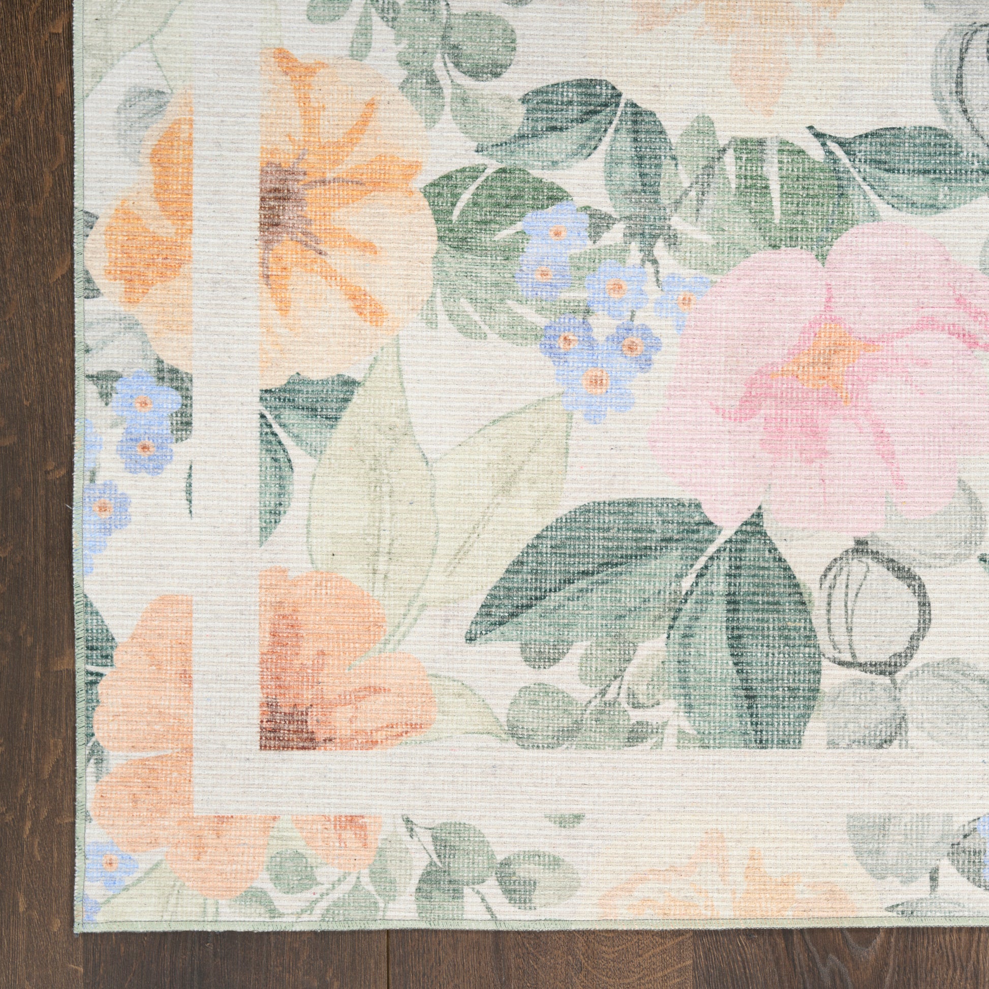 Pastel floral area rug with peach, pink, blue flowers & green leaves, white decorative border on dark wood floor.