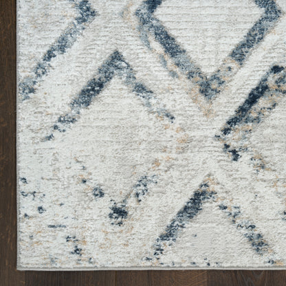 Cream plush rug with blue diamond geometric pattern, navy & light blue lines on dark wood floor.