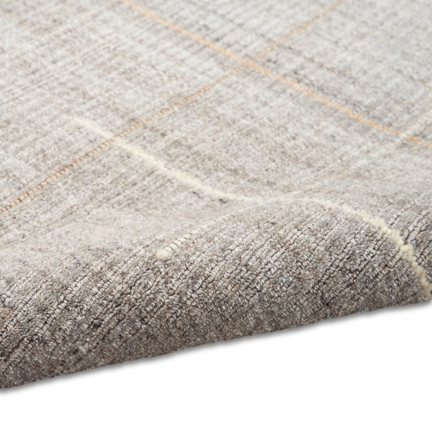 Neutral beige woven rug with subtle orange grid lines & soft textured pile; corner folded.