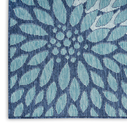 Close-up of a blue woven textile with teal petals in a radial floral pattern and navy outlines.