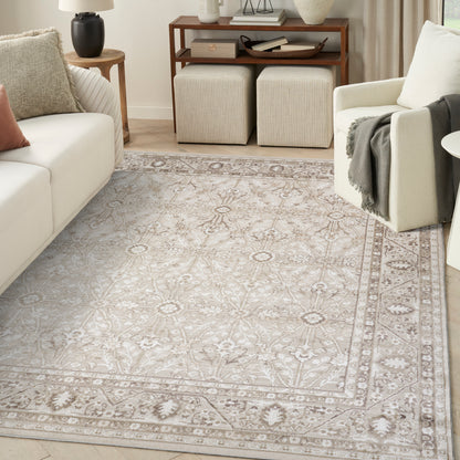 Soft beige patterned area rug with intricate border in a neutral living room featuring cream sofa and light armchair.