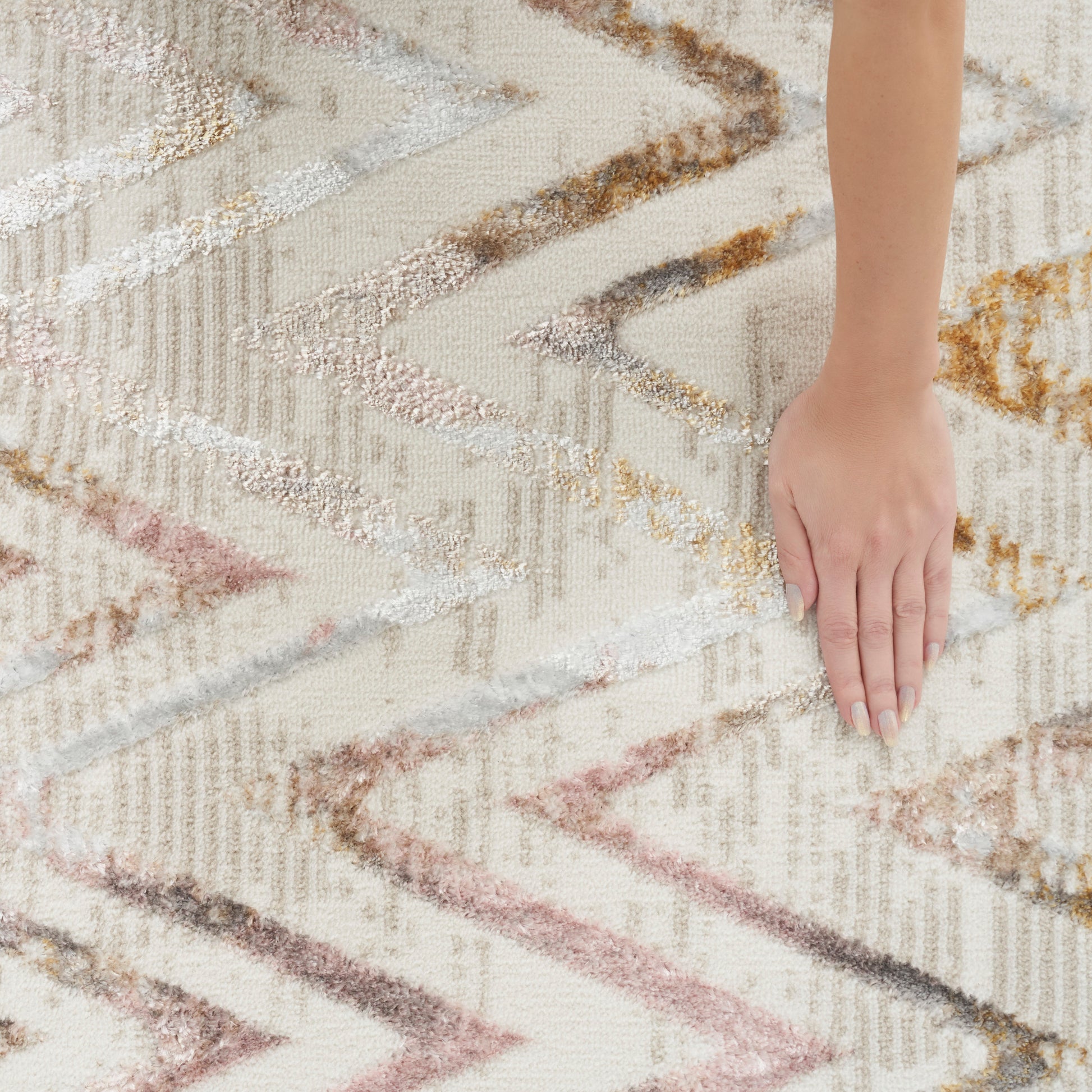 Ivory chevron-pattern rug with pink, brown and gold accents; soft textured pile.