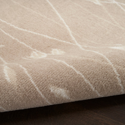 Beige plush area rug with white linear geometric pattern, soft texture resting on dark wooden floor.