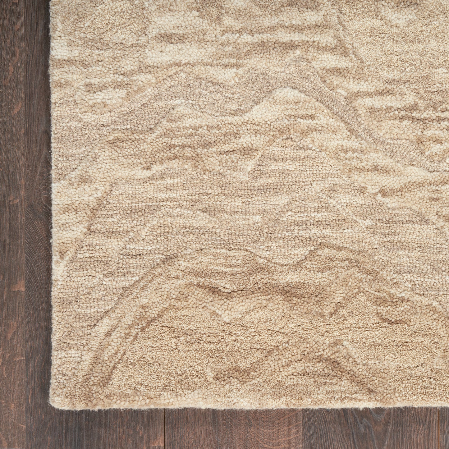 Beige textured shag rug with rippled pile on dark wood floor; rectangular and neutral-toned.