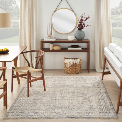 Mid-century living room with wooden dining chairs and console, round wall mirror, vase of dried blooms, woven basket, and neutral rug.