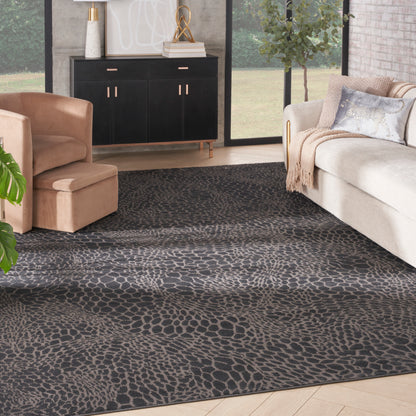 Dark grey rug with irregular pebble pattern in a modern living room with beige sofa, peach chair, black cabinet.