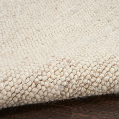 Cream boucle rug with dense loop pile & subtle brown flecks on a wooden floor.