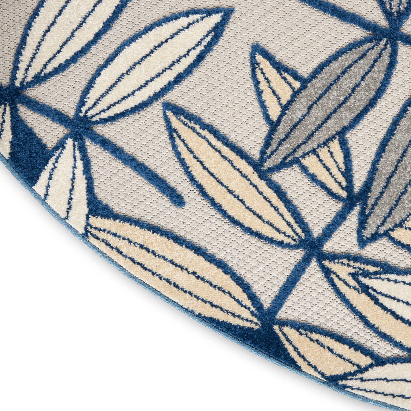 Close-up of a beige woven rug with blue leaf outlines and solid leaf shapes.