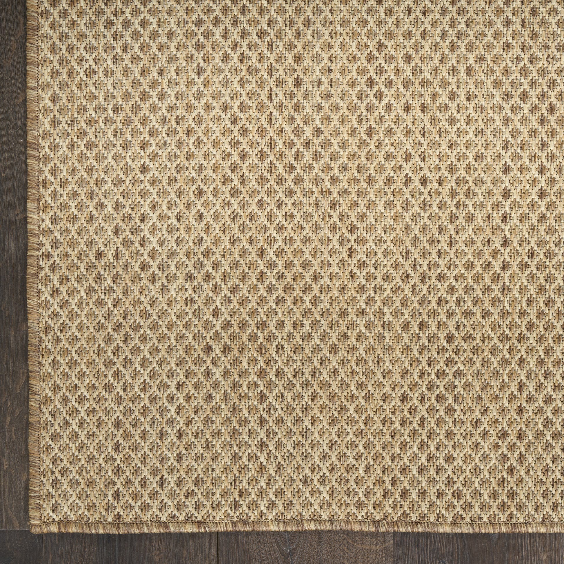 Natural jute runner rug with beige-brown diamond weave and fringed edge, on a dark wood floor, 10 ft long.