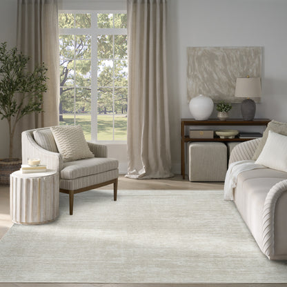 Neutral living room with a light beige area rug, cream sofa, striped armchair, and wooden console under a large window.
