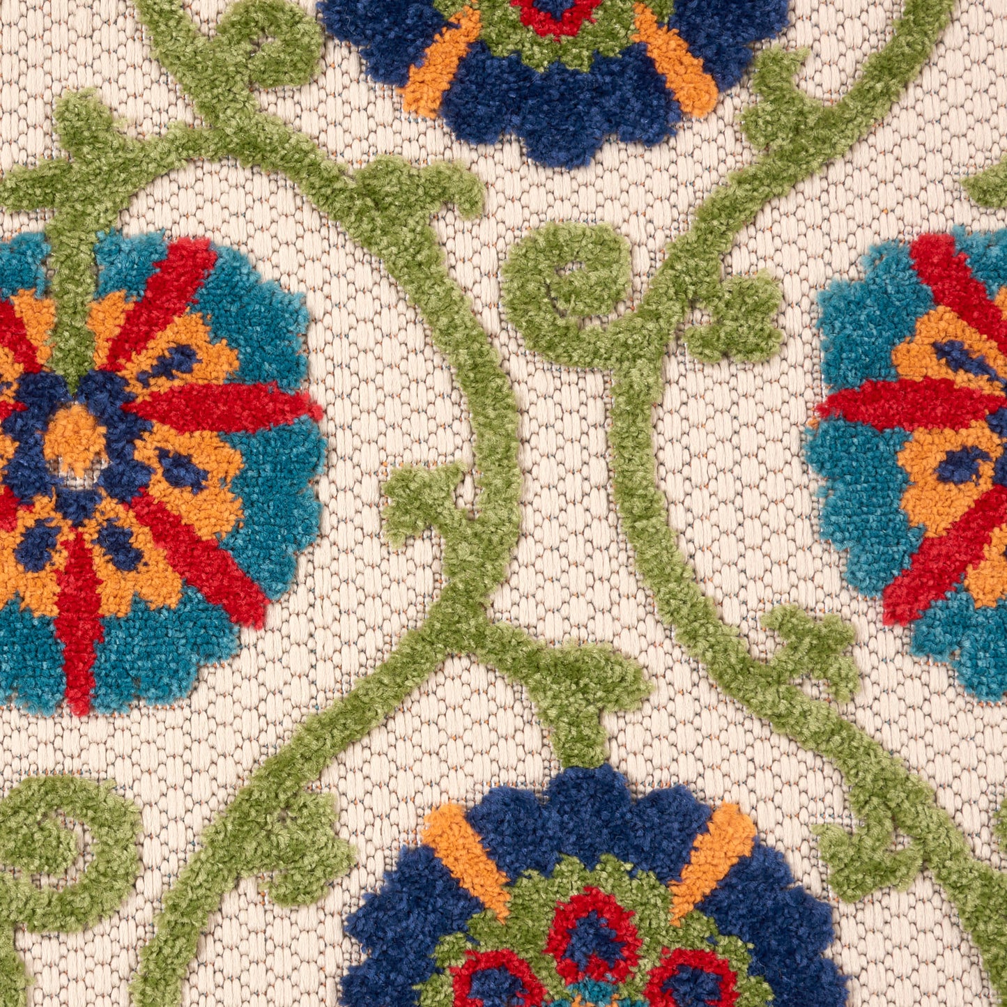 Beige jacquard rug with colorful floral embroidery: blue/teal flowers and orange centers on green vines.