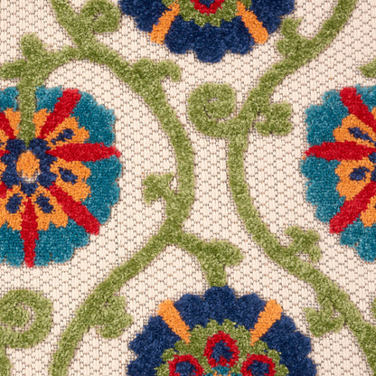 Beige jacquard rug with colorful floral embroidery: blue/teal flowers and orange centers on green vines.