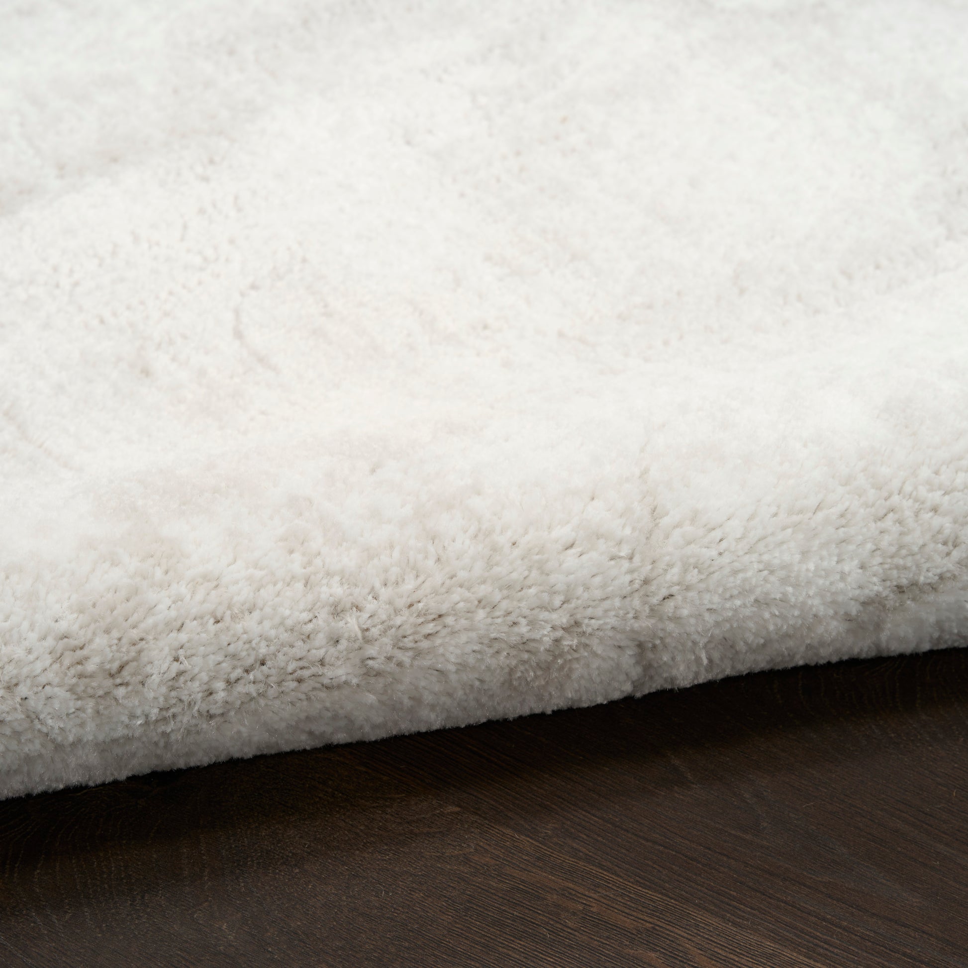 White plush shag rug with thick high pile on dark wood floor; cozy, modern decor.
