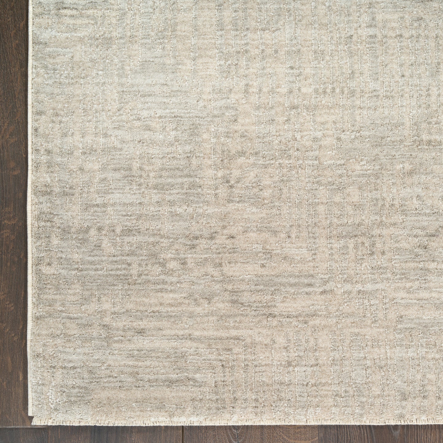 Rectangular beige textured area rug with subtle pattern over dark wood floor; modern flat-weave, versatile for living spaces.