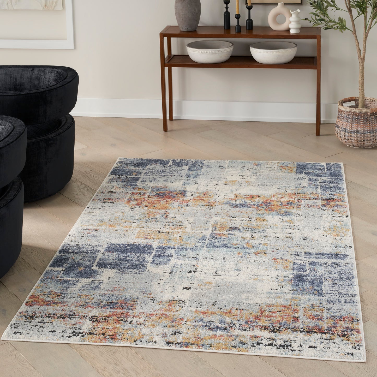 Abstract area rug with blue, orange, beige and ivory patches on light wood floor; modern distressed style for living room.