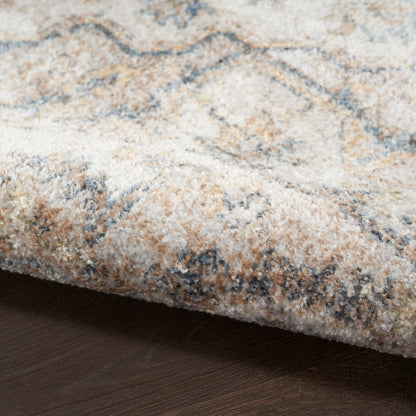 Close-up of a plush, patterned area rug with ivory, tan and blue tones on dark wood floor.