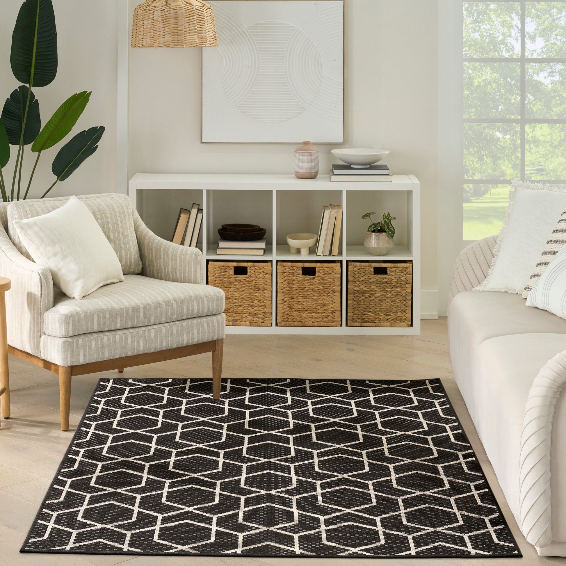 Black & white geometric area rug with hex pattern on light wood floor in a modern farmhouse living room.