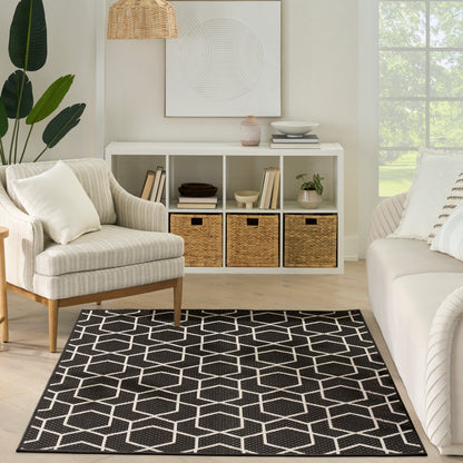 Black & white geometric area rug with hex pattern on light wood floor in a modern farmhouse living room.