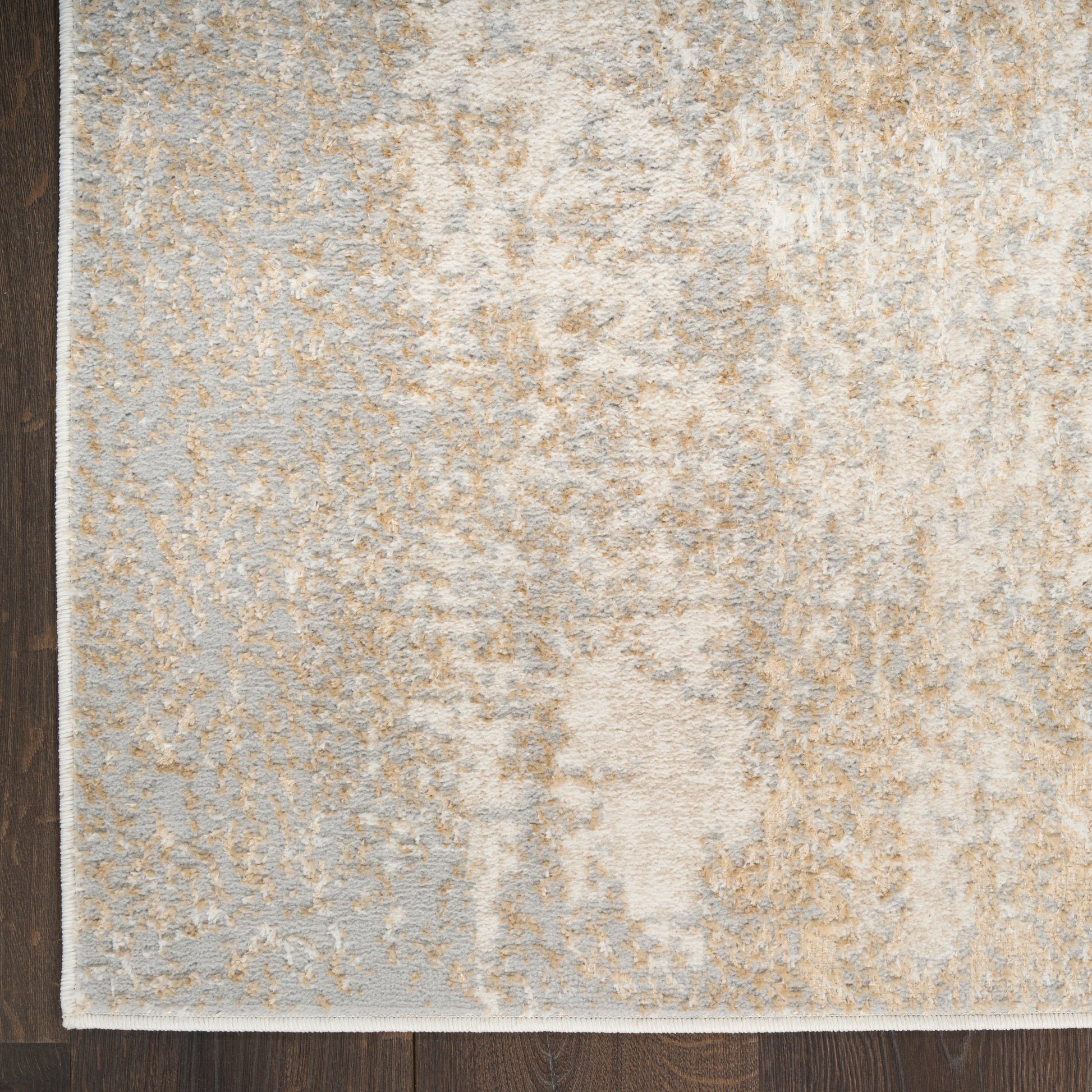 Muted-toned abstract area rug (5' x 7') in light gray and beige on a dark wood floor, contemporary style.