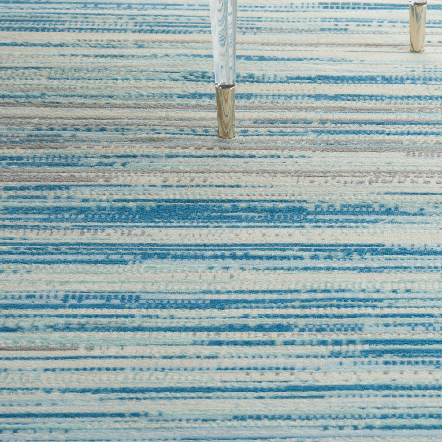 Rectangular blue striped rug with light to dark blue bands; modern living room floor covering.