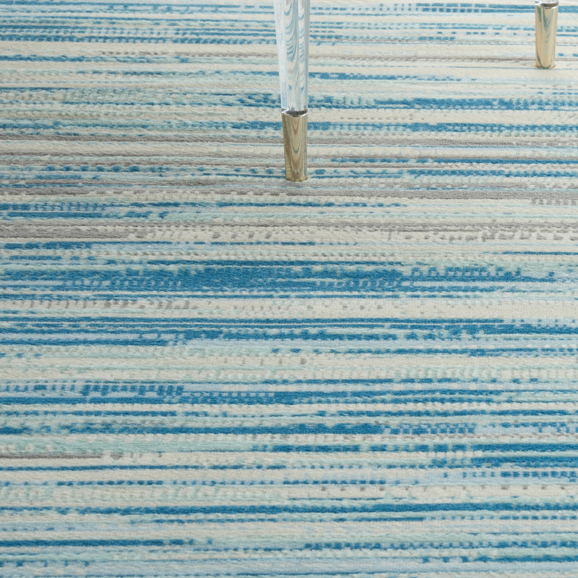 Rectangular blue striped rug with light to dark blue bands; modern living room floor covering.