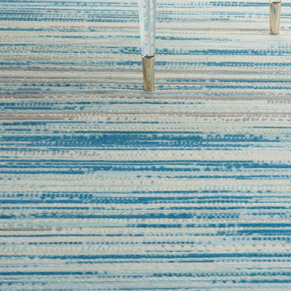 Rectangular blue striped rug with light to dark blue bands; modern living room floor covering.