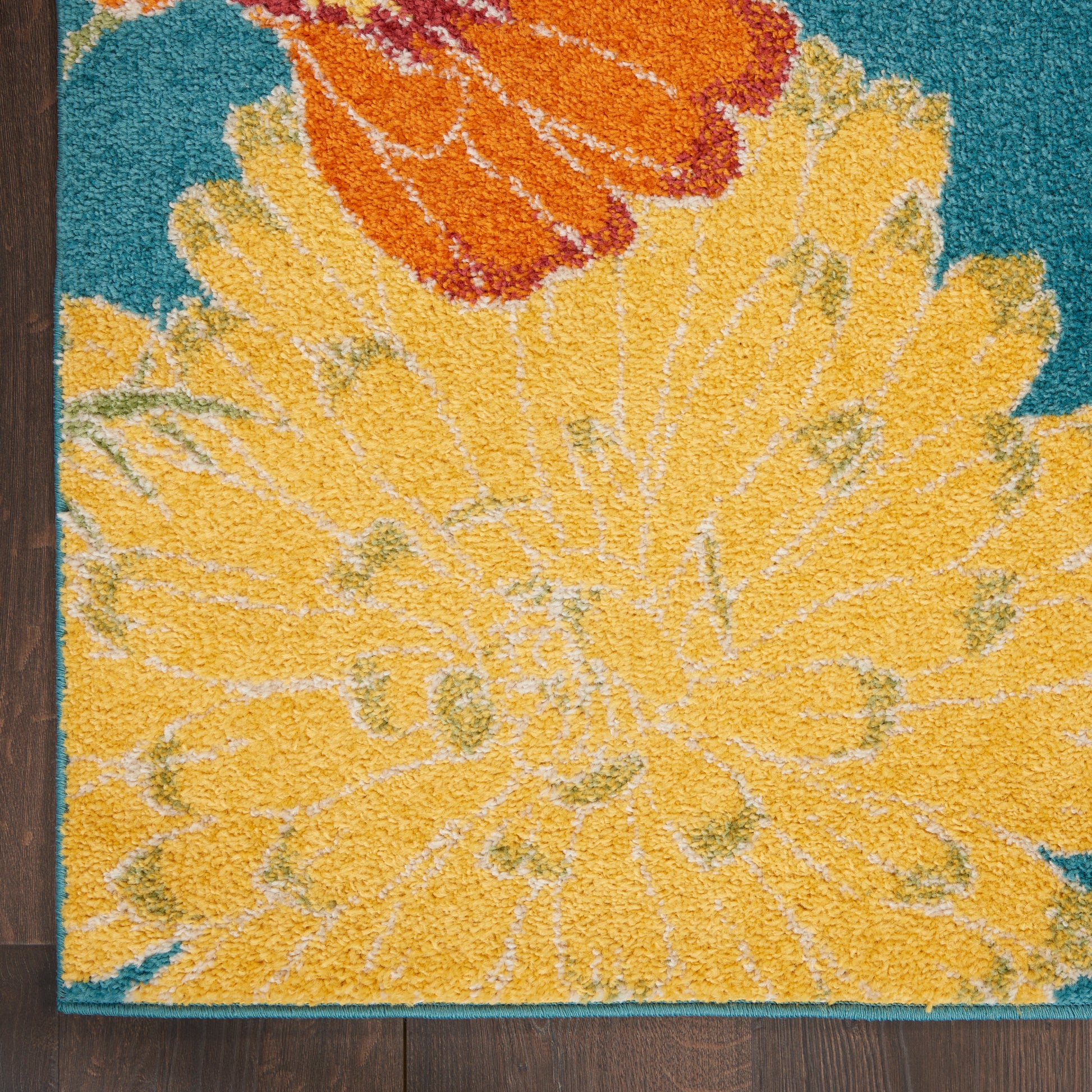 Rectangular shag rug with a large yellow flower and orange accents on a teal background; soft plush pile.